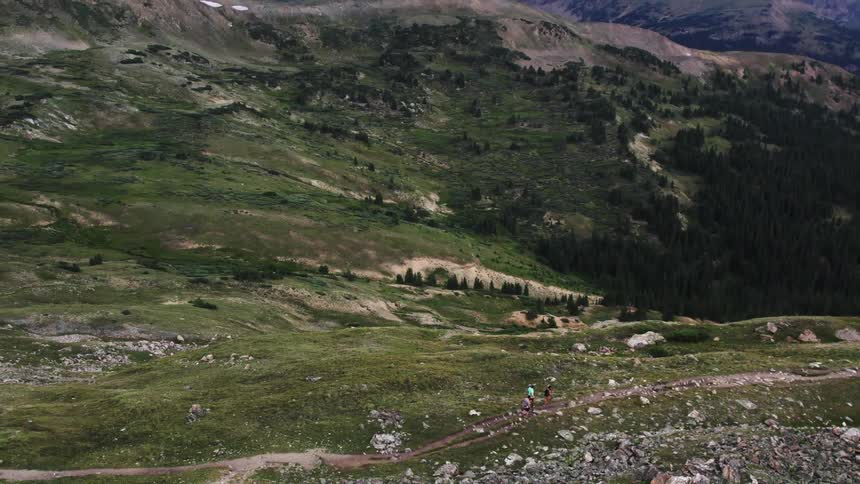 Aerial view of men running on dirt track on mountain
