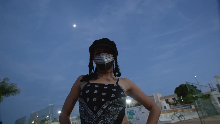 A woman in a face mask posing outdoors at a skate park
