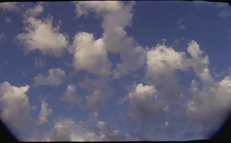 Fluffy clouds fill the sky on a sunny day shot on 16mm film