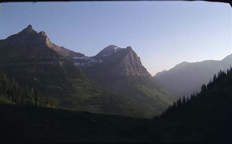 Mountain peaks with a dusting of snow above tree lined slopes at glacier national park