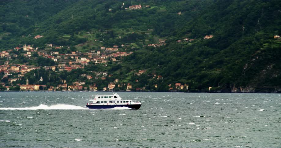 Boat travels on sea water next to coastal town