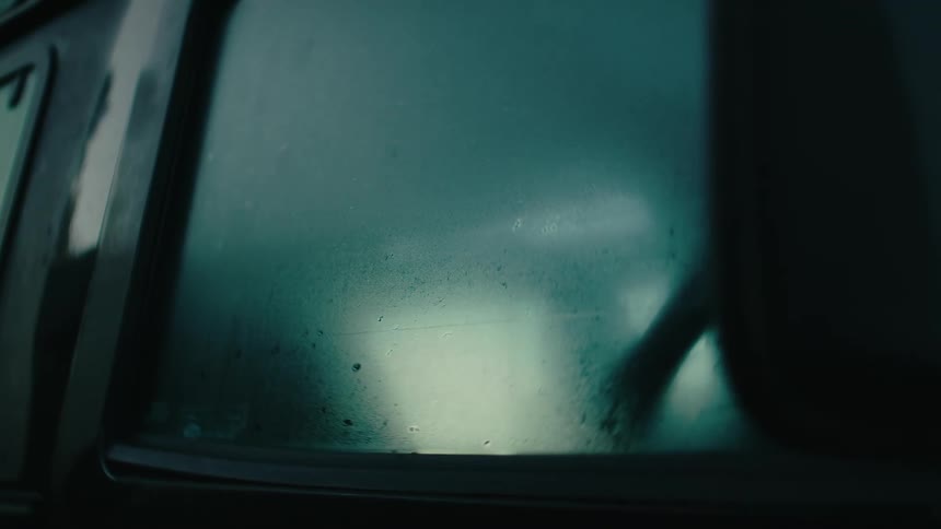 Close up of a fogged up window on a dimly lit aera
