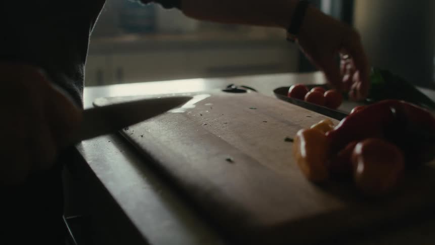 Person slices produce on wooden chopping board set on counter