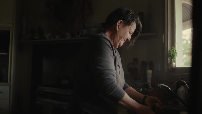 A woman washing potatoes at a kitchen sink at home