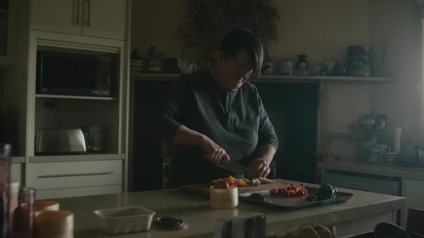 A woman is cutting food in the kitchen