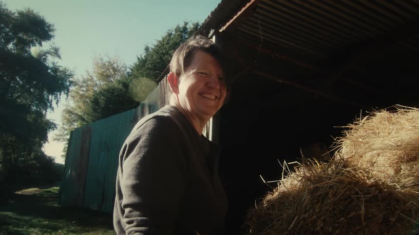 A farmer smiling and laughing while loading hay
