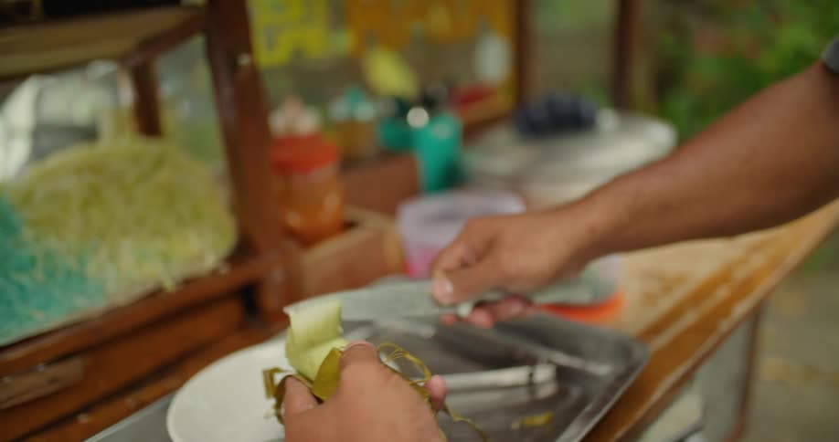 Man cuts banana into thick slices and places them in a bowl as another person waits