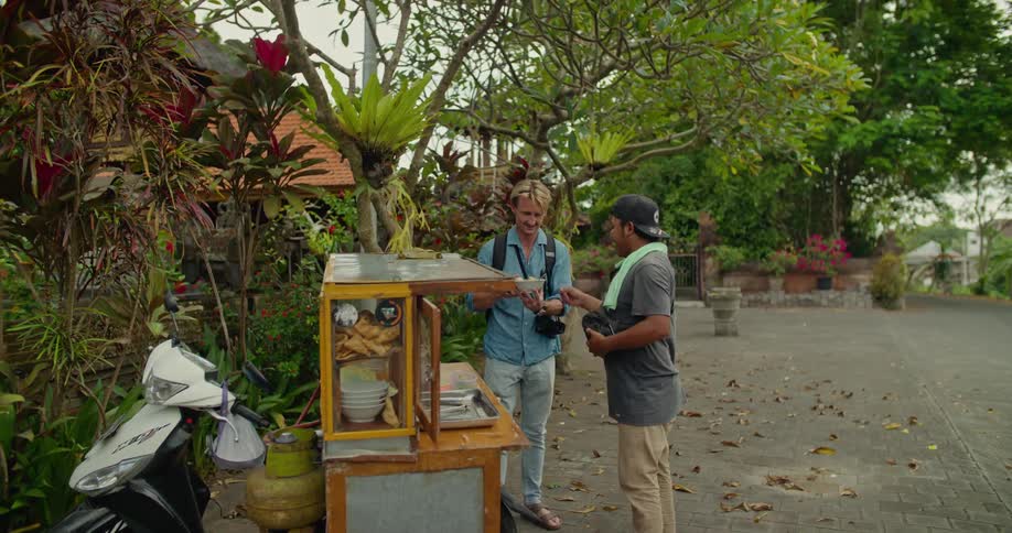 Tourist standing in front of a lush green garden has a taste of the local cuisine on vacation