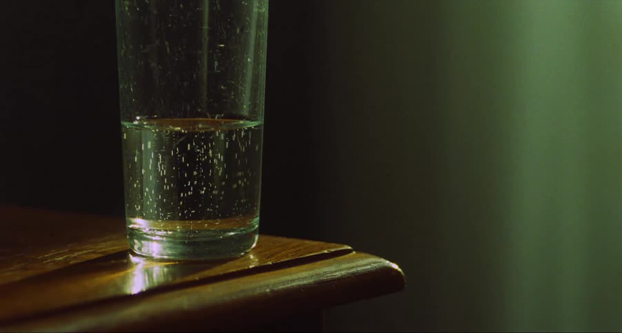 A glass of sparkling water sits on a side table in a house