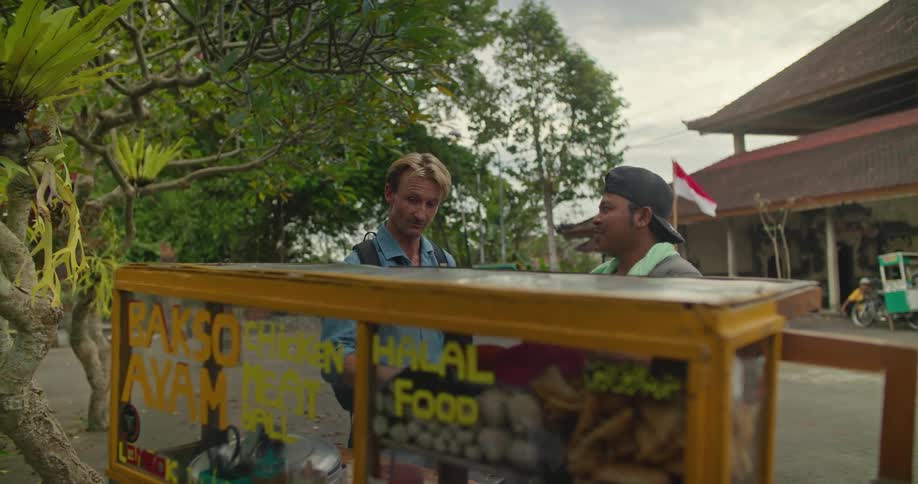 Tourist talk to a local vendor selling food on the streets of a small town