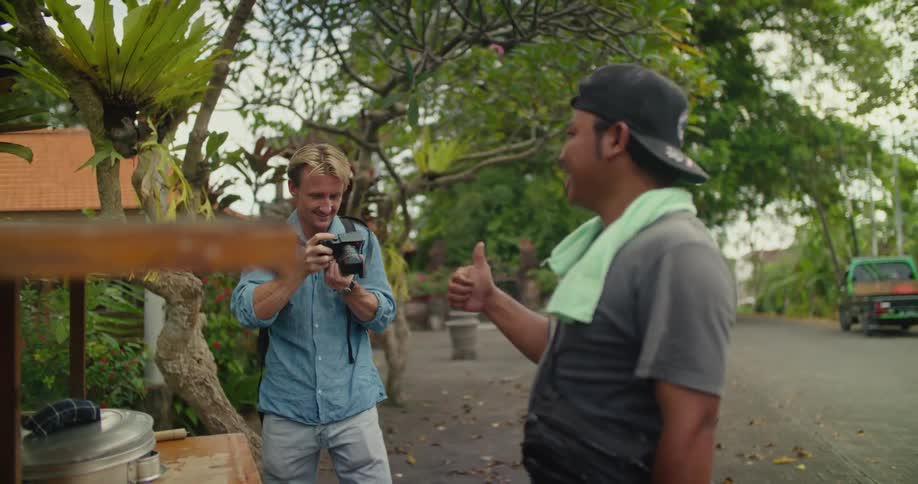 Male photographer takes picture of street food cart vendor
