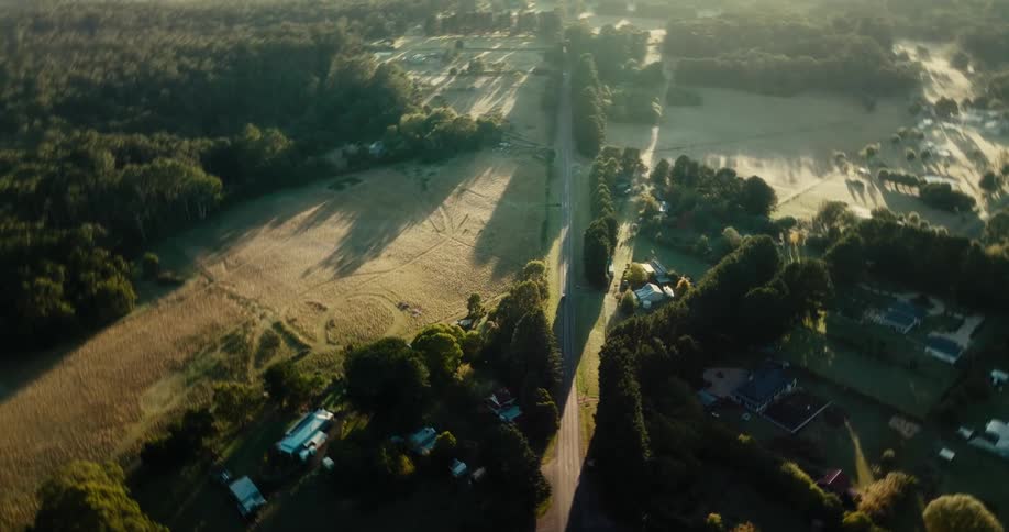 Car drives on a road through the farm fields of a small town in the morning