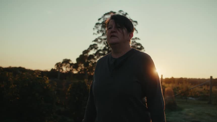 A middle aged woman walking in a rural area at sunrise