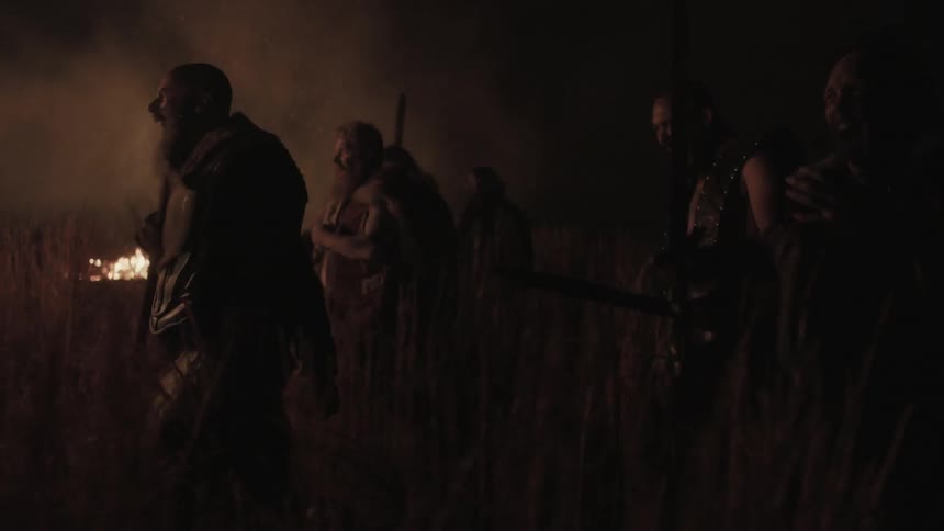 Men with weapons charge across a field at night