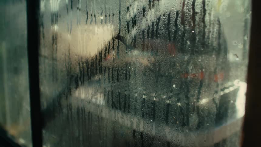Farmer working inside a greenhouse in the farm at morning seen through fogged glass