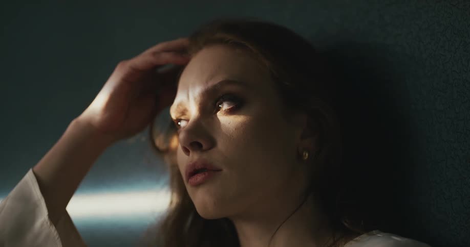 A woman has her hand on her head as she moves her eyes around and looking depressed