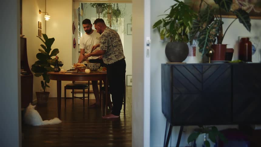 Two men serve dinner on table