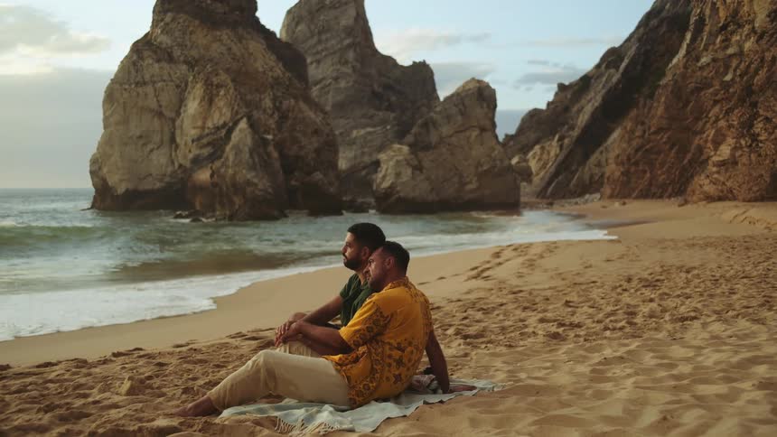 Two men are sitting at the beach together