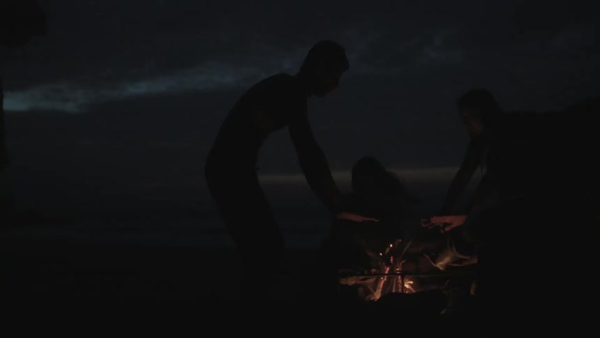 People build a fire on a beach at night