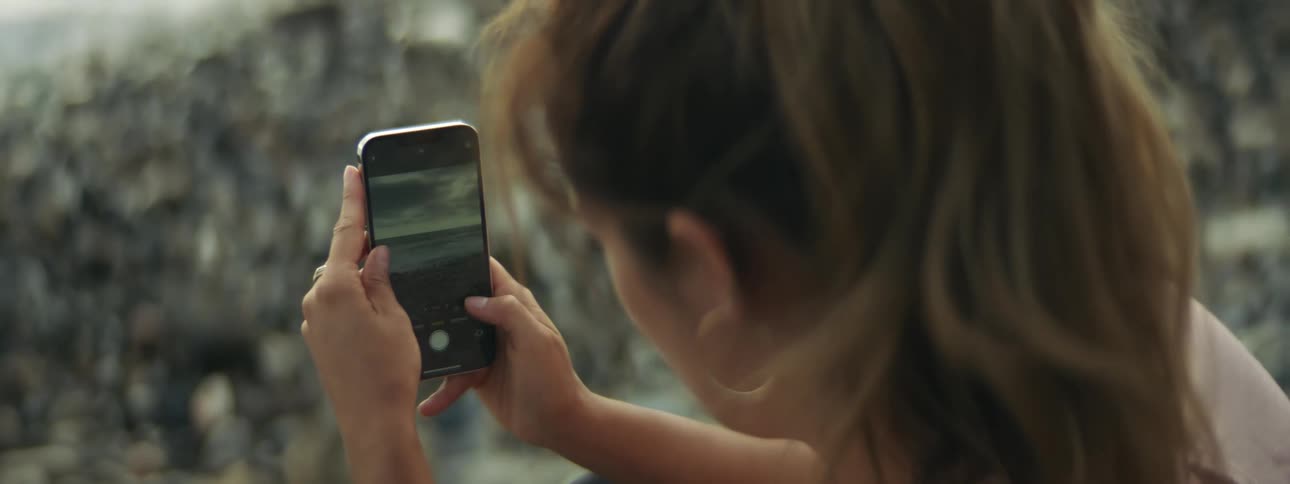 Young woman takes pictures of a beach with her smartphone