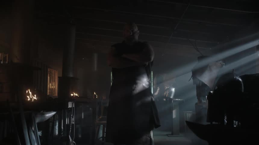 A man has his arms folded in a dark room