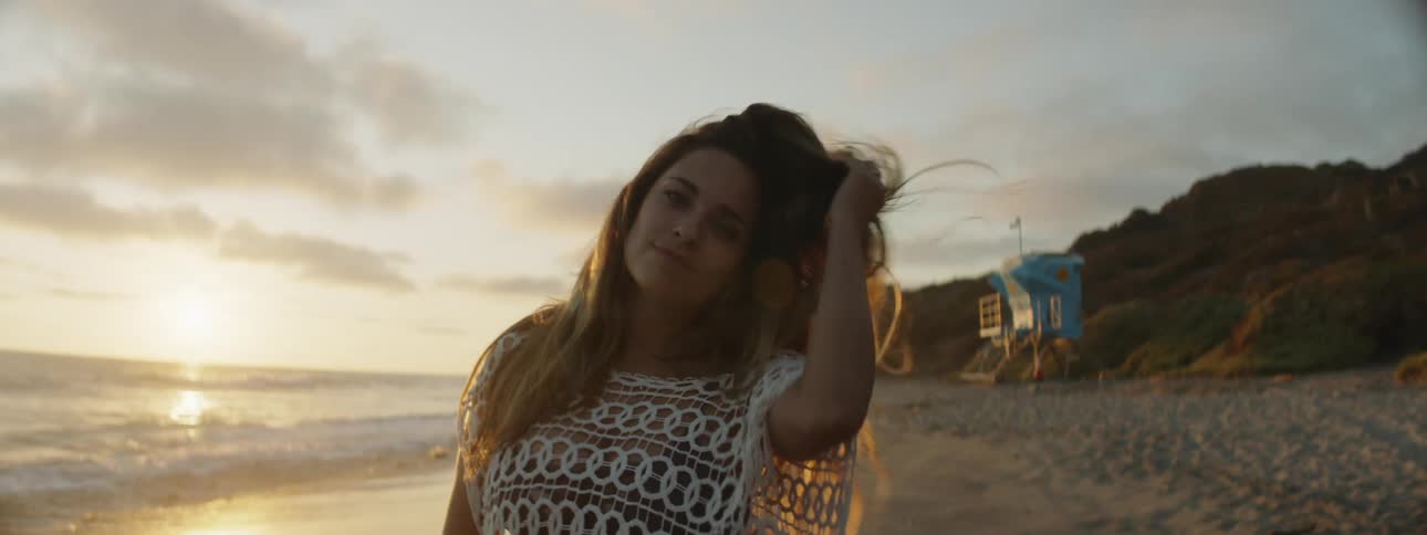 A woman tousles her hair while posing on the beach