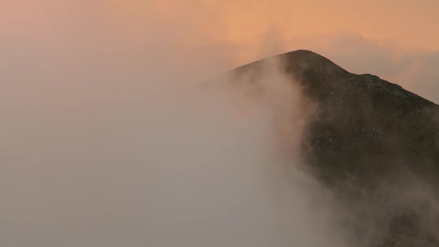 Clouds moving across a hillside and covering it completely