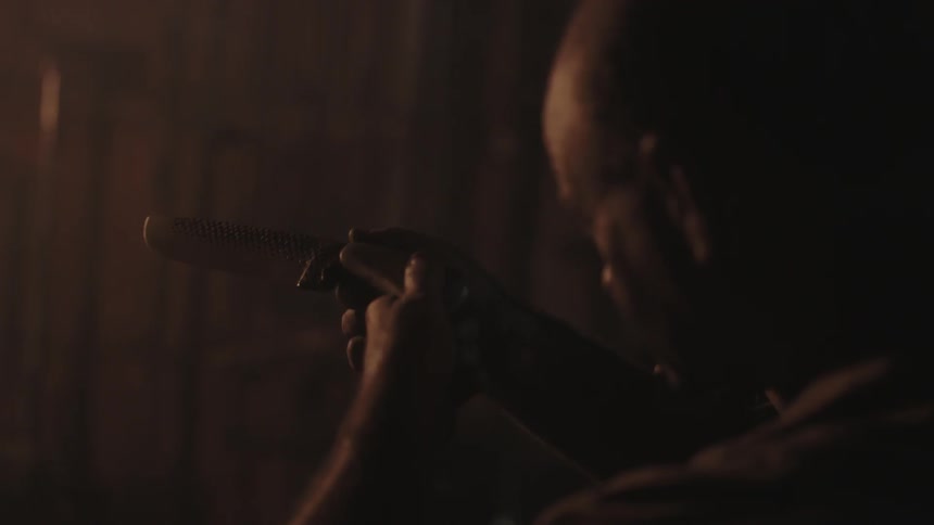A man is examining a knife in a dark area