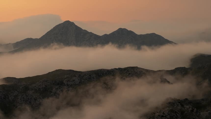 The valley between two mountain ranges is filled with thick clouds