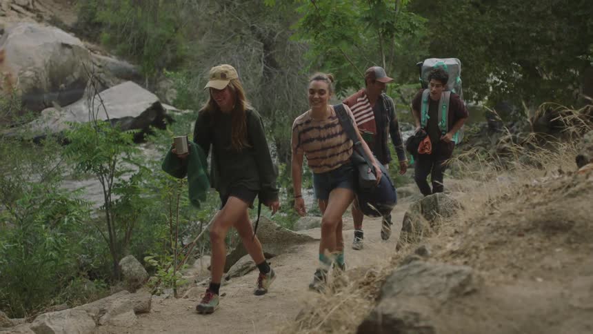 Group of young teenage friends hiking on a trail in the mountains next to a river