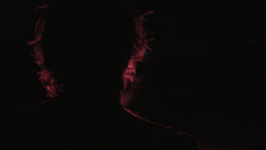 A shirtless man holds a flare at night