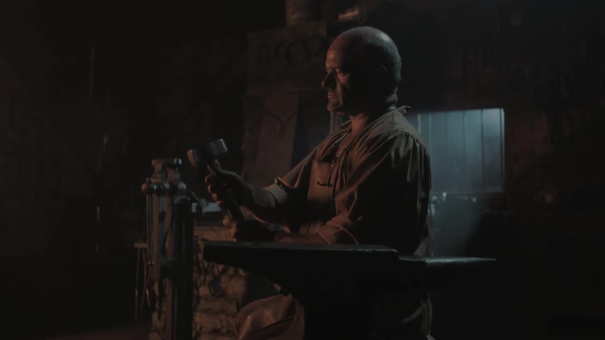 A blacksmith examines his hammer