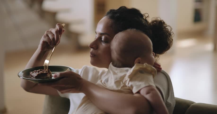 Mother eats and simultaneously holds and comforts baby