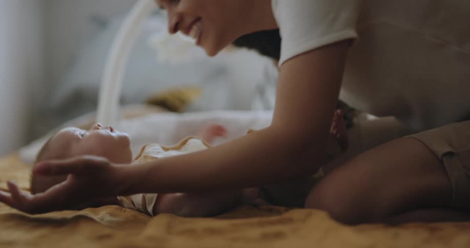 A mother smiling and kissing her newborn baby