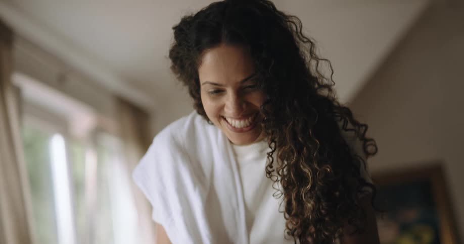 A woman smiles at her baby while changing its diaper