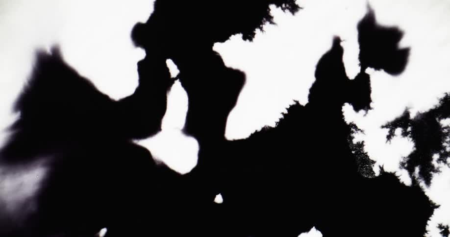 Black ink spreads on a white surface