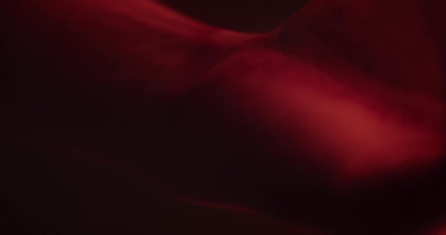 A red illuminated object fades and moves in the darkness