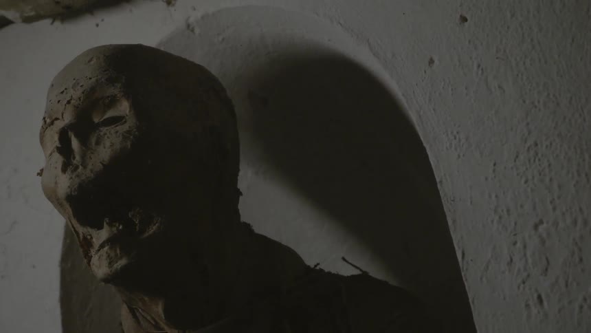A rotted corpse is leaning against a wall
