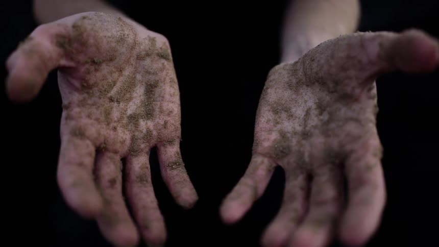 A man showing his hands dirty with dirt and dust