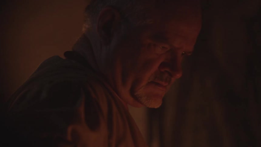 A man looks down frowning in a dark area