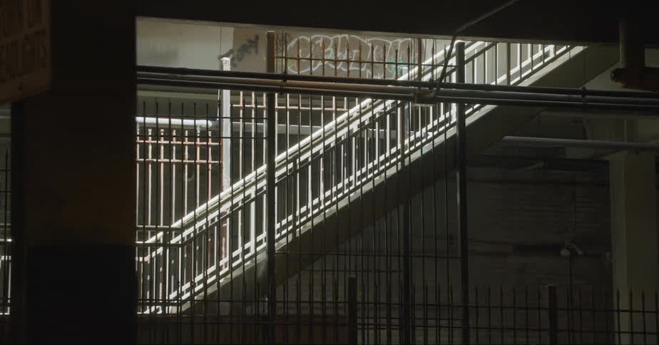 Metal bars cover sides of large open area around staircase with graffiti on some walls