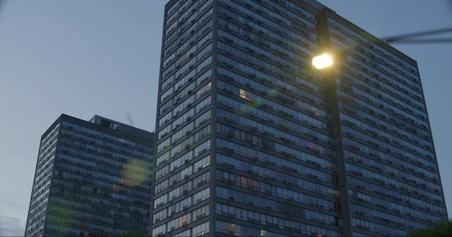 Lights come up in some apartments at a large downtown building