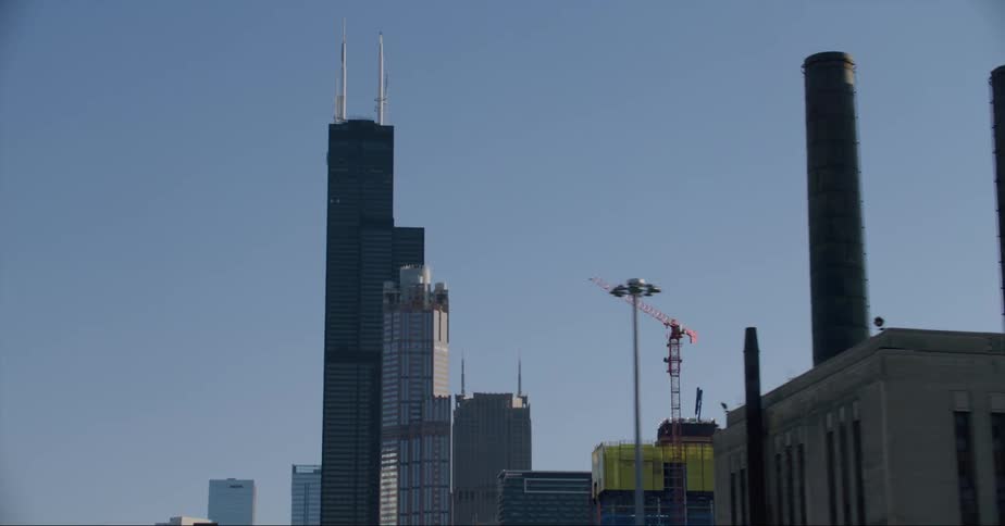 A construction crane on top of a building surrounded by high rise office buildings in a city