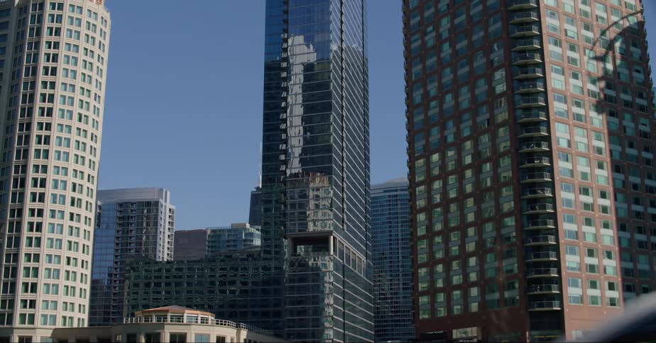 One skyscraper casts shadow on another building as other downtown skyscrapers reflect their surroundings
