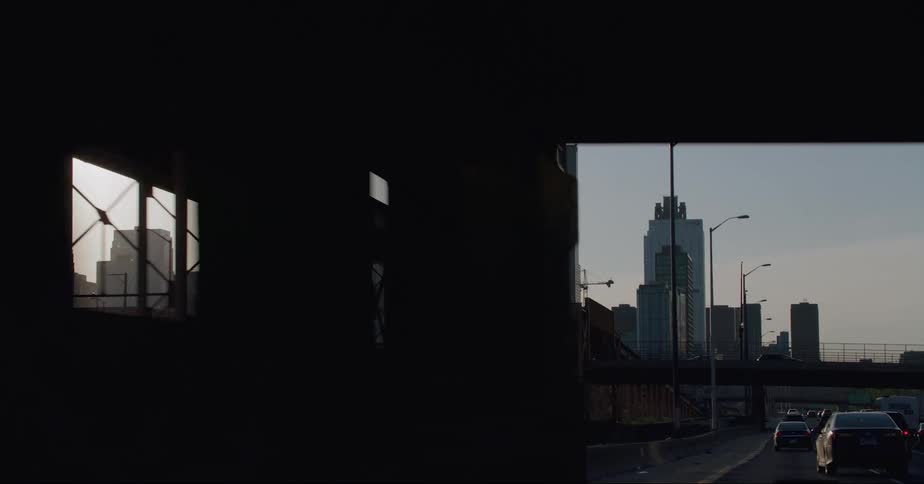 Vehicles drive under a bridge on a highway headed toward downtown