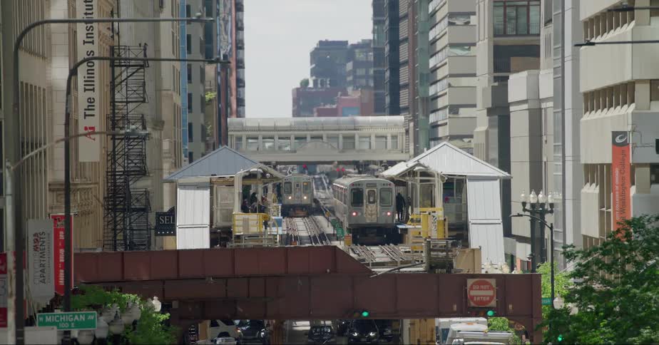 Trains run through a station in a downtown neighborhood