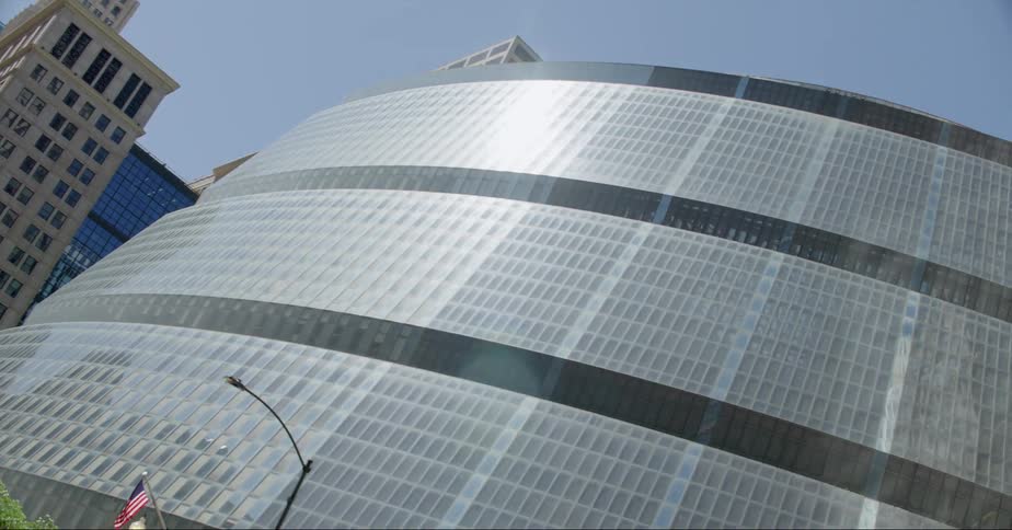 Sunlight reflects on the large glass facade of a skyscraper in the city under a blue sky