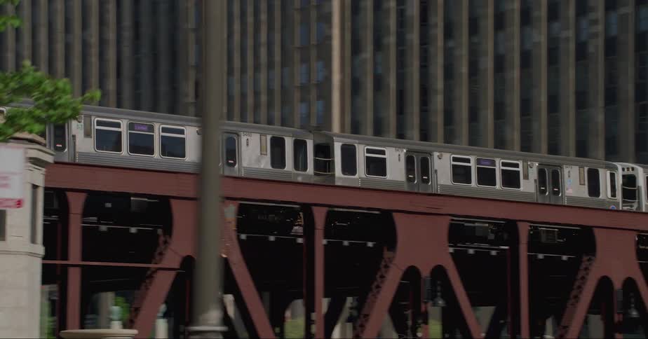 Passenger train runs on tracks seen from vehicle passing under bridge in the city
