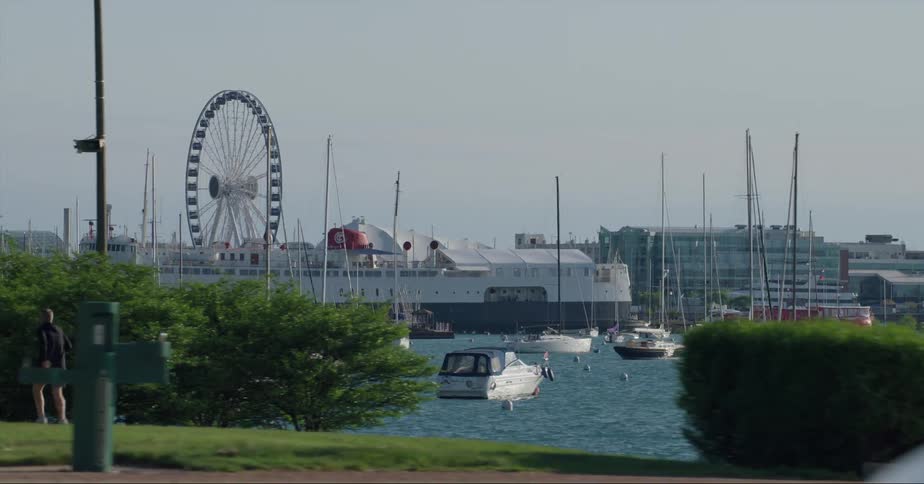 Joggers run near marina with ferris wheel on the opposite shore near ship and buildings