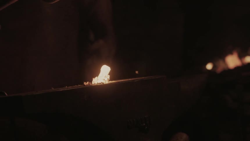 A molten piece of metal is hit with a hammer